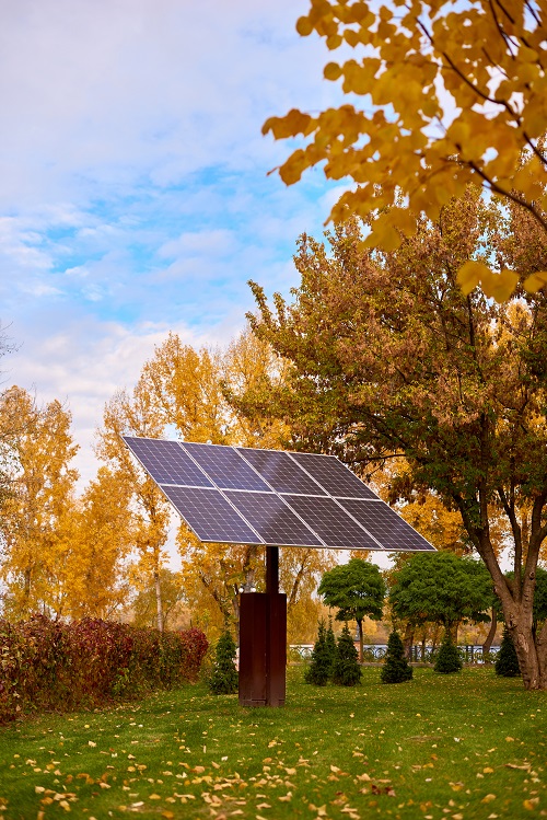 Solar panels, photovoltaic - alternative electricity source. Beautiful yellow trees in autumn. solar panels in city park on sunny fall day
